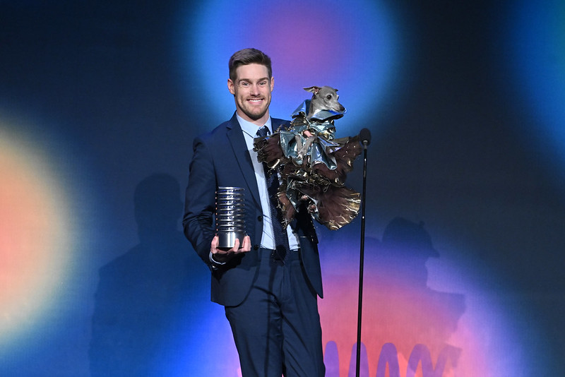 Man holding both a Webby Award and dog wearing a silver shirt